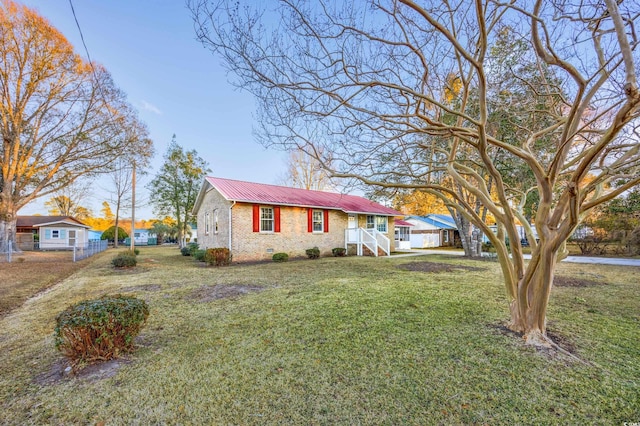 view of front of property with a front lawn, fence, metal roof, crawl space, and brick siding