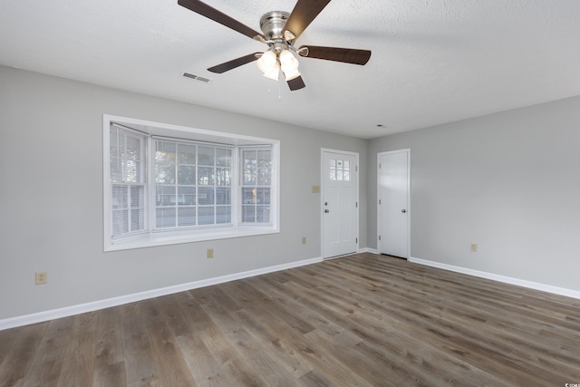 foyer entrance with visible vents, a textured ceiling, baseboards, and wood finished floors