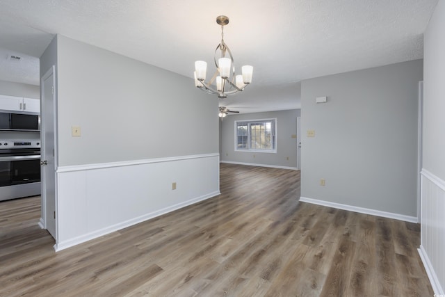 unfurnished room featuring baseboards, wood finished floors, visible vents, and a textured ceiling