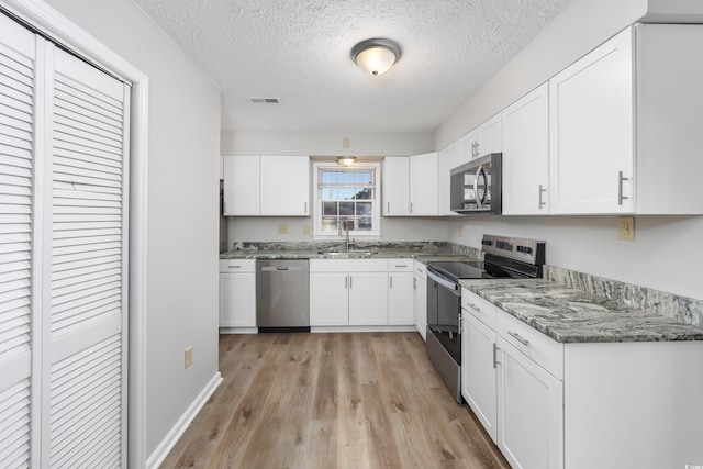 kitchen with white cabinetry, stainless steel appliances, and a sink