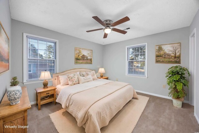 carpeted bedroom featuring multiple windows, visible vents, baseboards, and ceiling fan