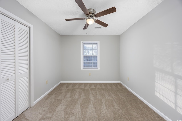 unfurnished bedroom with visible vents, baseboards, carpet, a closet, and a textured ceiling