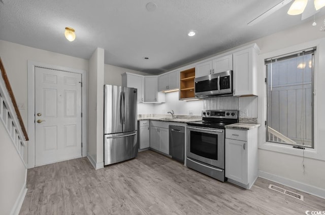 kitchen featuring light wood-type flooring, visible vents, open shelves, stainless steel appliances, and baseboards