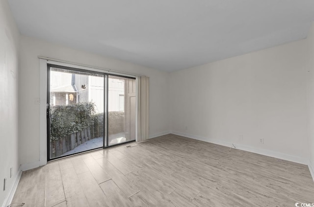 spare room featuring baseboards and light wood finished floors