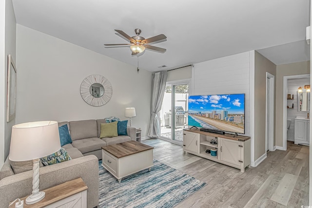 living area featuring light wood-style flooring, baseboards, and ceiling fan