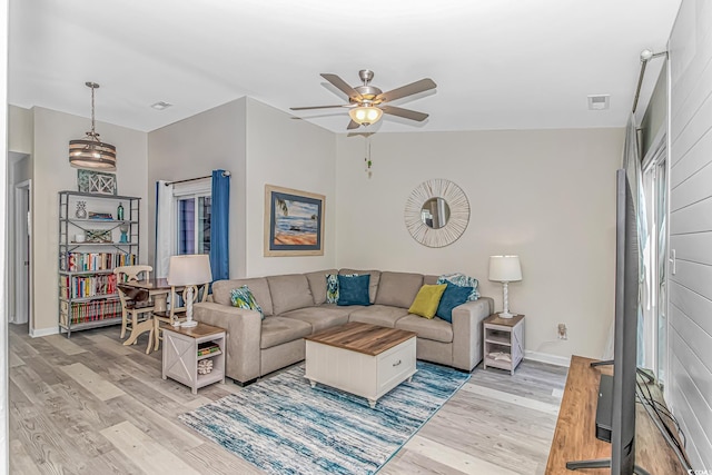 living room featuring ceiling fan, light wood finished floors, visible vents, and baseboards