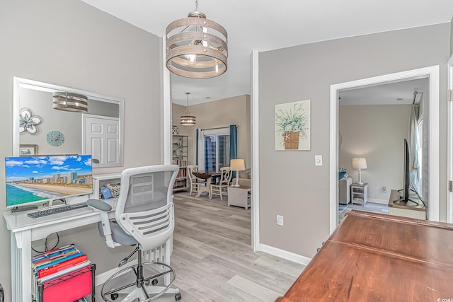 office space with baseboards, light wood finished floors, and an inviting chandelier