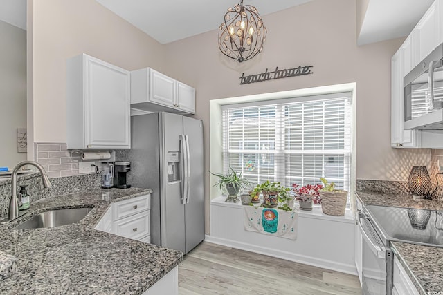 kitchen featuring appliances with stainless steel finishes, a sink, white cabinetry, and tasteful backsplash