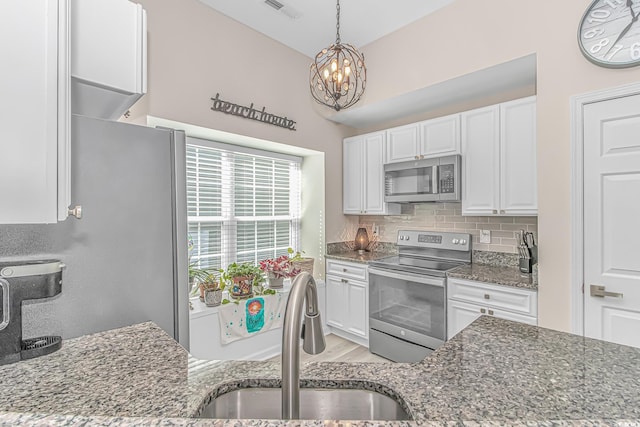 1006 Charles St, North Myrtle Beach, SC 29582 - kitchen featuring stainless steel appliances, dark stone countertops, white cabinetry, and a chandelier