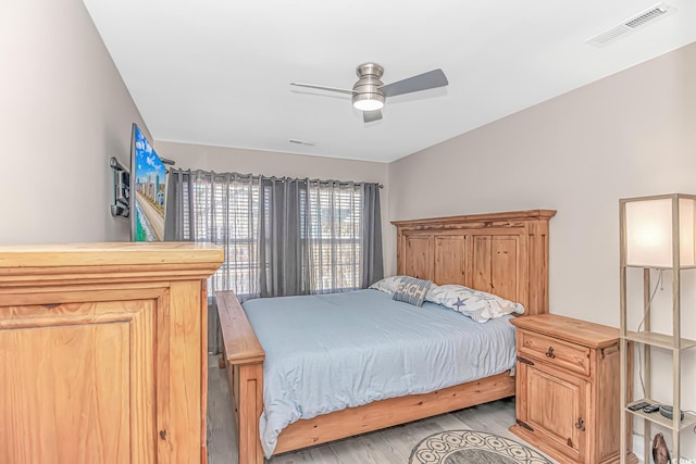 bedroom with light wood finished floors, visible vents, and a ceiling fan