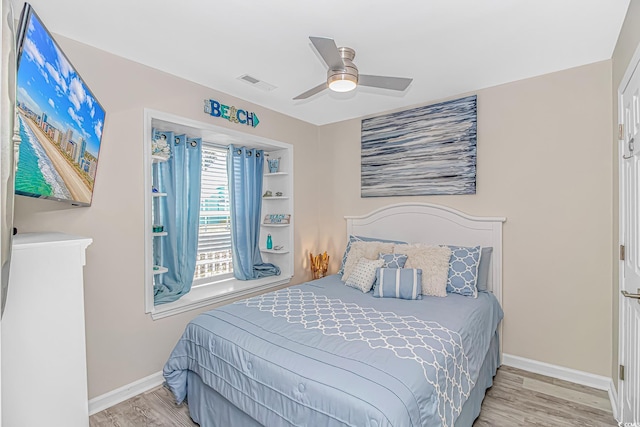 bedroom featuring a ceiling fan, wood finished floors, visible vents, and baseboards