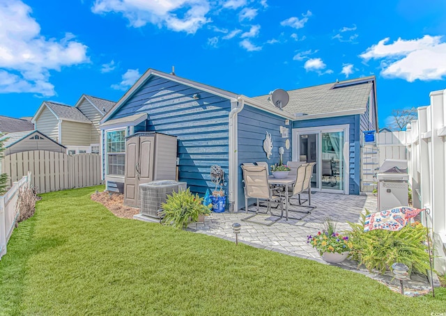 rear view of house featuring a patio, a lawn, central AC, a fenced backyard, and an outdoor structure