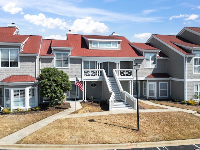 townhome / multi-family property with stairway and a shingled roof