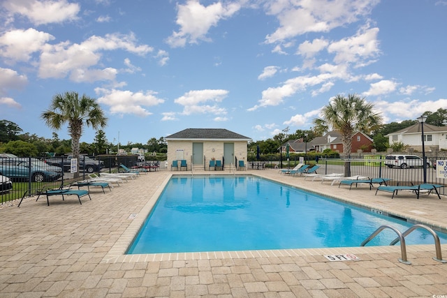 community pool with a patio area and fence