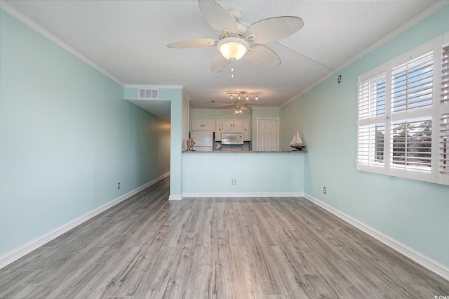 unfurnished living room featuring visible vents, ceiling fan, baseboards, ornamental molding, and wood finished floors