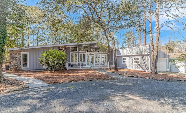 mid-century home with board and batten siding and a sunroom