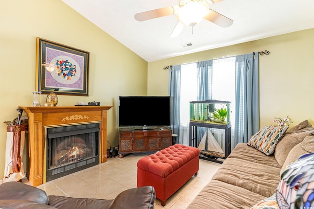 tiled living area with ceiling fan, vaulted ceiling, a warm lit fireplace, and visible vents