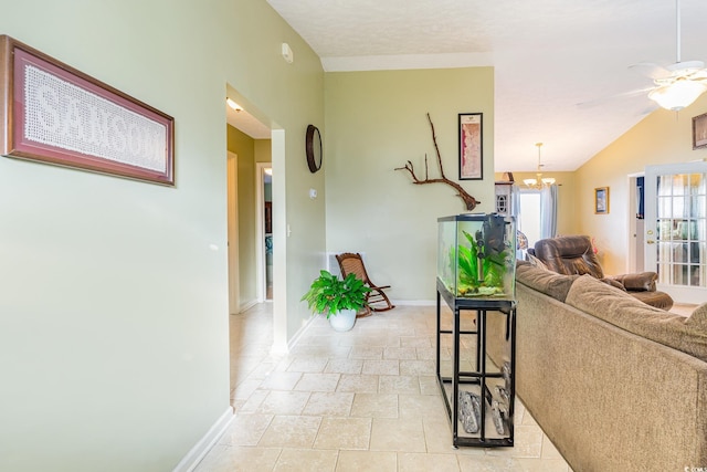 living area with ceiling fan with notable chandelier, baseboards, and vaulted ceiling