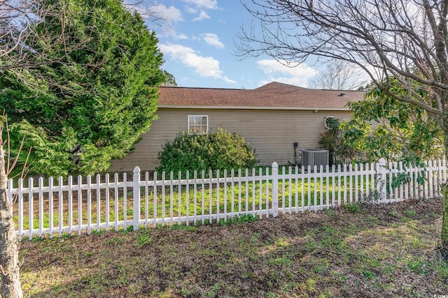 view of side of home featuring central AC unit, fence, and a shingled roof