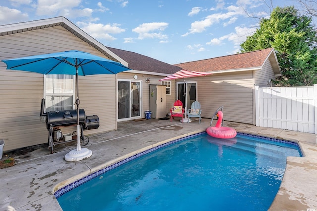 outdoor pool featuring a grill, fence, and a patio