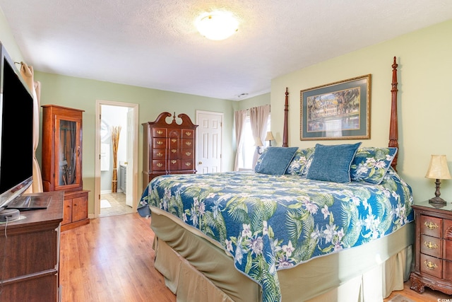 bedroom featuring connected bathroom and light wood-style flooring