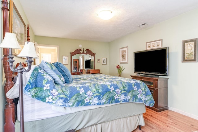 bedroom featuring baseboards, wood finished floors, and visible vents