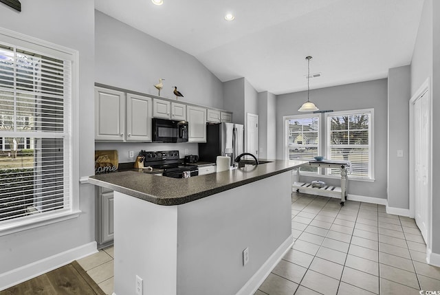 kitchen featuring dark countertops, decorative light fixtures, lofted ceiling, light tile patterned floors, and black appliances