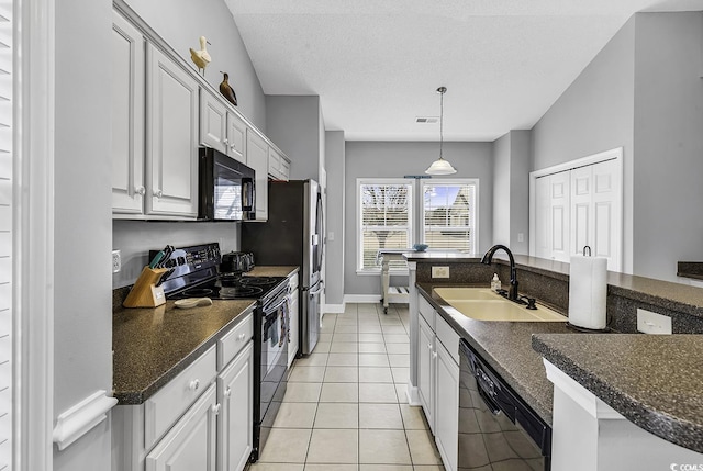 kitchen featuring light tile patterned floors, a sink, black appliances, pendant lighting, and a textured ceiling