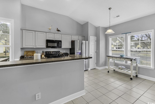 kitchen with dark countertops, black appliances, a wealth of natural light, light tile patterned flooring, and white cabinetry