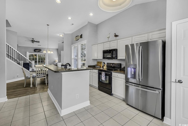 kitchen featuring light tile patterned floors, dark countertops, black appliances, and white cabinets