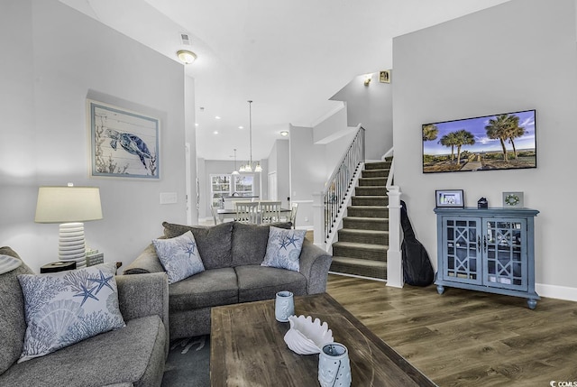 living area with an inviting chandelier, stairway, wood finished floors, and baseboards