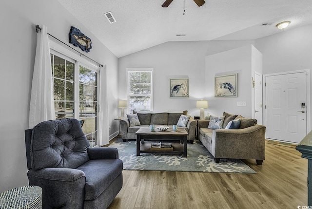 living room with lofted ceiling, wood finished floors, visible vents, and a textured ceiling