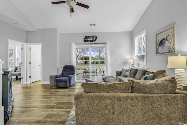 living area with lofted ceiling, wood finished floors, visible vents, and a wealth of natural light