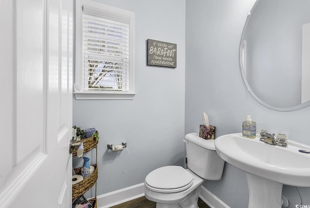 half bath with baseboards and toilet