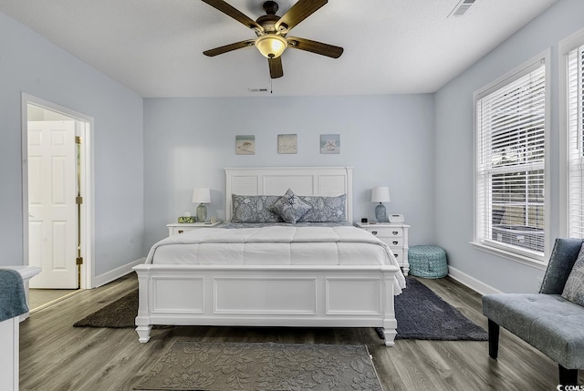 bedroom with a ceiling fan, wood finished floors, visible vents, and baseboards