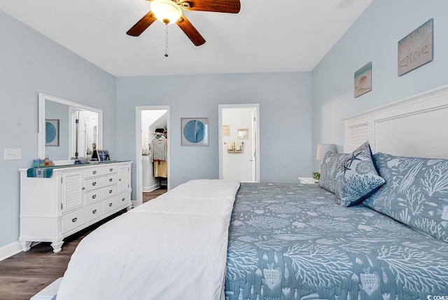 bedroom featuring a spacious closet, connected bathroom, ceiling fan, baseboards, and dark wood finished floors