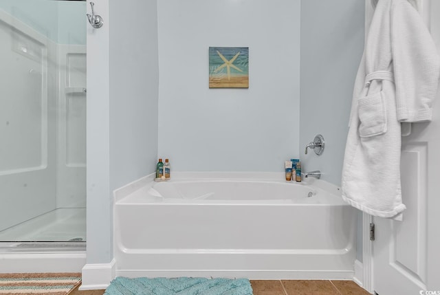 bathroom featuring tile patterned flooring, a stall shower, and a garden tub