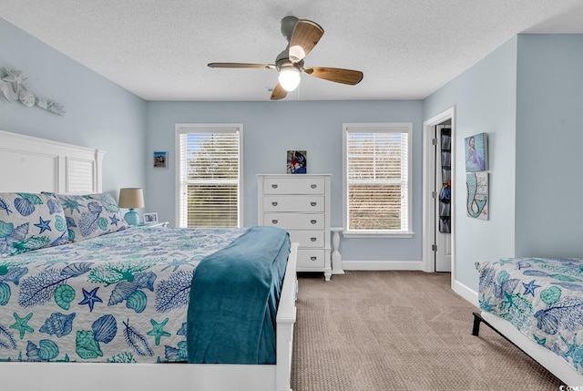 carpeted bedroom featuring a textured ceiling, baseboards, and a ceiling fan