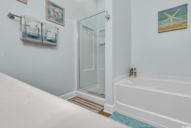 full bath featuring a garden tub, baseboards, and a stall shower