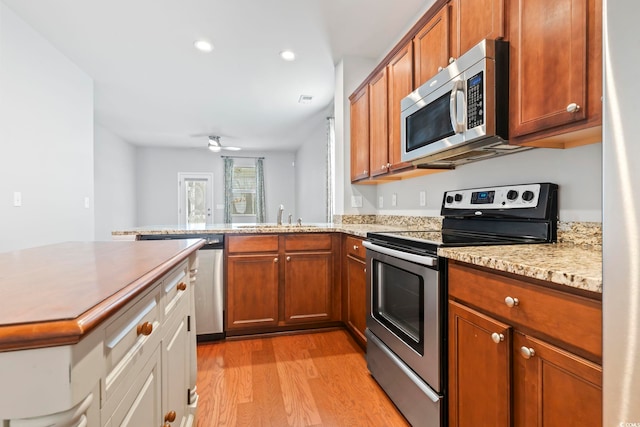 kitchen with light wood-style flooring, brown cabinetry, appliances with stainless steel finishes, and a sink