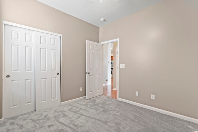 unfurnished bedroom with carpet flooring, baseboards, a closet, and ceiling fan