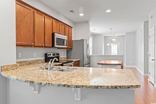 kitchen with brown cabinetry, visible vents, a peninsula, recessed lighting, and stainless steel appliances