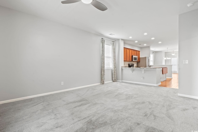 unfurnished living room with recessed lighting, baseboards, light carpet, and ceiling fan