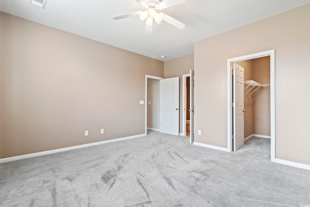 unfurnished bedroom with visible vents, baseboards, ceiling fan, a walk in closet, and carpet flooring