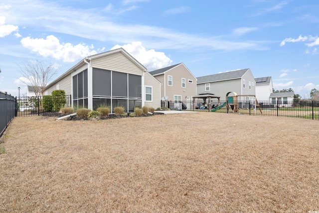 rear view of house with a playground, fence private yard, and a sunroom