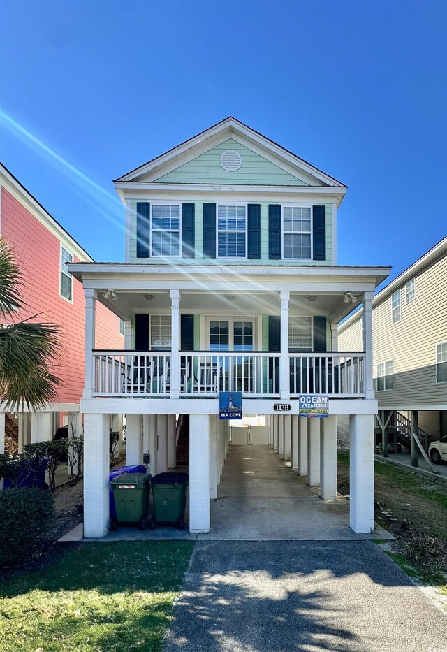 113B 13th Ave N, Surfside Beach, SC 29575 - raised beach house with asphalt driveway, a porch, a carport, and stairs