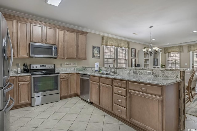 kitchen featuring a peninsula, a sink, appliances with stainless steel finishes, brown cabinets, and a chandelier