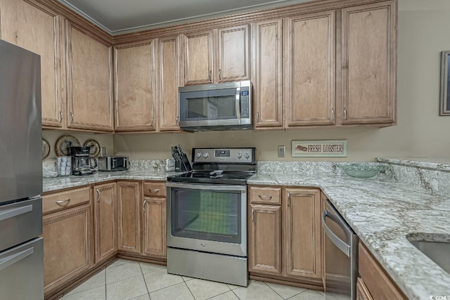 kitchen featuring light tile patterned floors, light stone counters, appliances with stainless steel finishes, and brown cabinetry