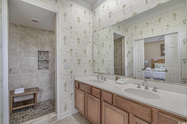 bathroom featuring tiled shower, connected bathroom, wallpapered walls, and a sink