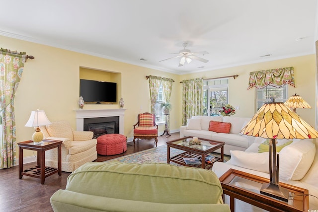 living area featuring baseboards, wood finished floors, a glass covered fireplace, and crown molding